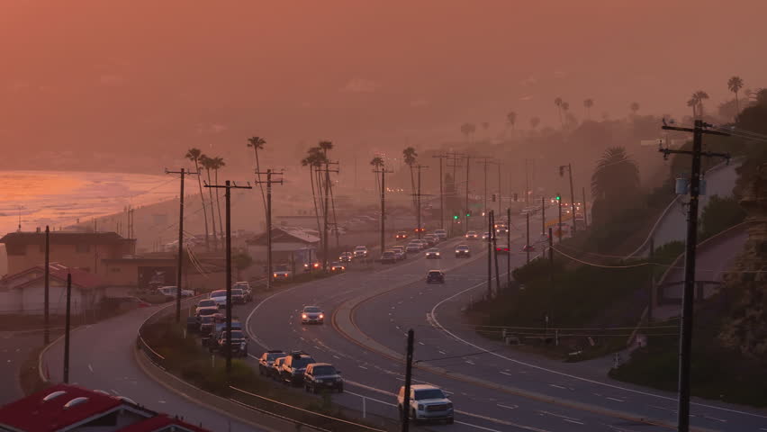 Capturing the stunning beauty of Malibu, California from above at sunset, featuring the coastal road, palm trees, and serene evening atmosphere, providing a picturesque and relaxing view
