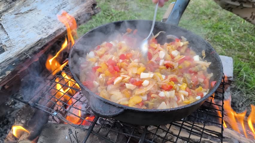 cooking over a campfire with fire and smoke.