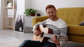 Young red haired man relaxing at home playing guitar. Leisure and hobbies concept - Powered by Shutterstock - Get 15% off with code: PIKWIZARD15