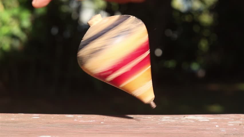 Photography for dynamic scenes, spin, a colorful spinning top spinning on a wooden table, falling down and colliding with the table.