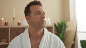 Man wearing a white bathrobe relaxing in a spa room with candles and plants, performing a facial massage - Powered by Shutterstock - Get 15% off with code: PIKWIZARD15