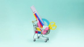 Shopping trolley with stationery items and school supplies moving on blue background. back to school and education background concept. Shopping cart, supermarket trolley. Stop motion animation video - Powered by Shutterstock - Get 15% off with code: PIKWIZARD15
