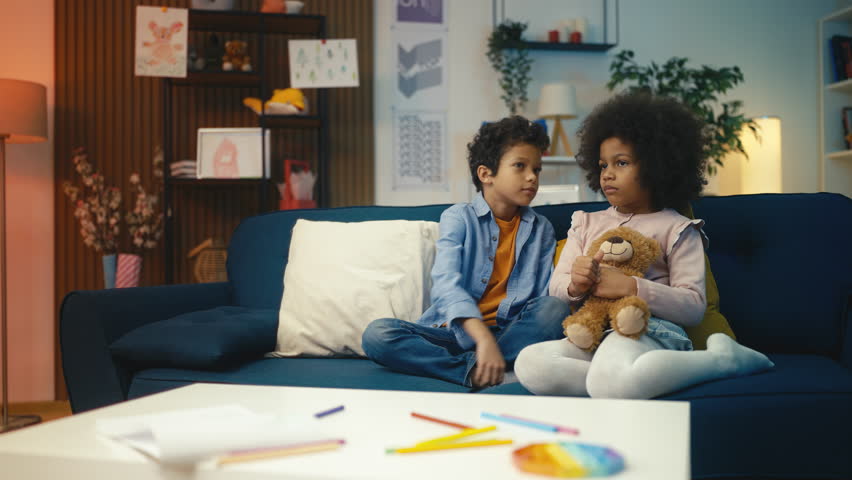 Happy African American boy whispers a secret in sister