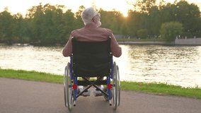 Sad senior man sitting in wheelchair walking on road in city park outdoor, back view. Old paralyzed man in chair for people with disability feel depressed. Lonely elderly sick man sits on wheelchair - Powered by Shutterstock - Get 15% off with code: PIKWIZARD15