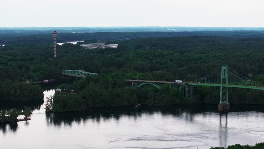 Aerial view of Thousand Islands International Bridge from Canada to the US over St. Lawrence River New York to southeastern Ontario summer with vehicle traffic crossing over water and forest