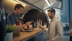 Food Truck Male Staff Member Serving Coffee and Food to a Young Man and a Female at a Modern City Location. Satisfied Customer Using a NFC Mobile Payment Application to Pay for the Order - Powered by Shutterstock - Get 15% off with code: PIKWIZARD15