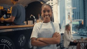 Brazilian Black Female Barista Standing Next to a Stylish Urban Food and Coffee Truck, Posing with Arms Crossed, Looking at Camera and Smiling. Beautiful Young Girl Working in Street Food Industry - Powered by Shutterstock - Get 15% off with code: PIKWIZARD15