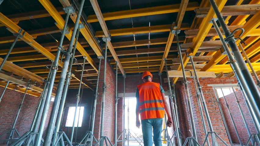 The builder goes inside the building under construction. Builder inside the house. The builder goes to the construction site.