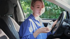 Driver woman in the car is using her mobile phone. Cheerful young blond woman is sitting into a vehicle with a smartphone in the hand and talking to the phone via video call - Powered by Shutterstock - Get 15% off with code: PIKWIZARD15