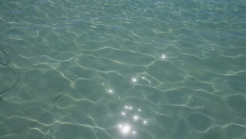Clear turquoise water with sun reflections in porto cesareo, italy, showcasing the serene beauty of the salento coastline in puglia during a sunny day.