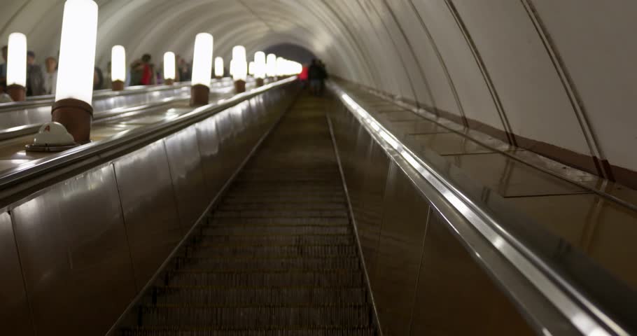 The camera rides up an escalator in a dark subway room in a large metropolis. Empty stairs in the subway moving up. A cinematic shot in a darkened subway. High quality 4k footage