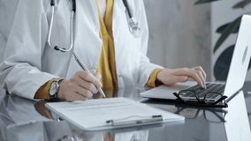 Doctor filling out medical forms while sitting at the glass desk. - Powered by Shutterstock - Get 15% off with code: PIKWIZARD15