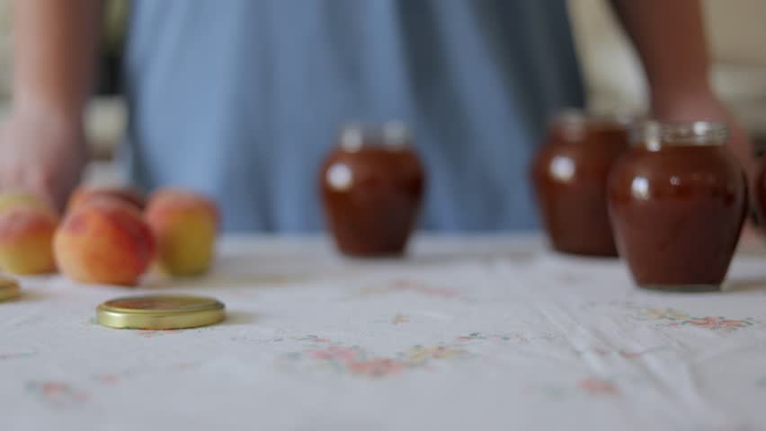 Female hands twist the metal lid on a glass jar with apricot jam. Homemade apricot jam.
