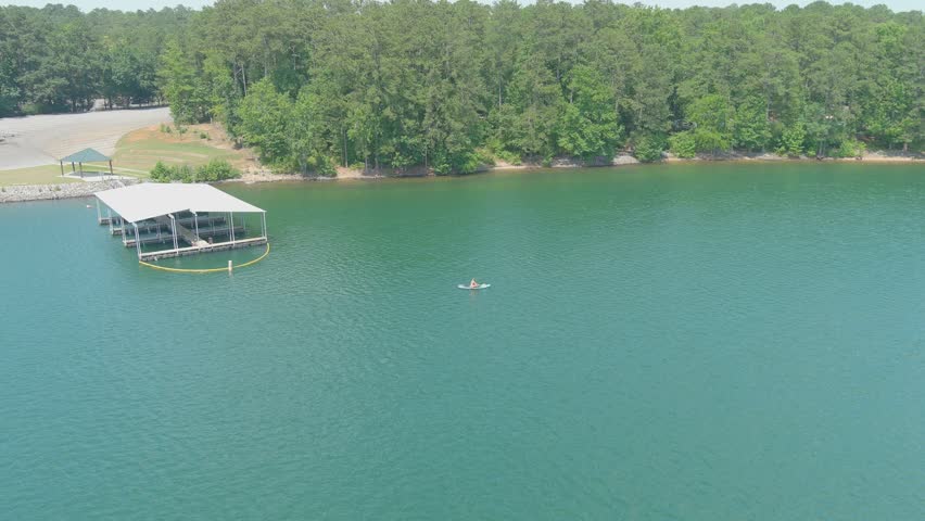 stunning aerial footage of the vast silky green waters of Lake Allatoona surrounded by lush green trees with boat docks along the banks of the lake at Victoria Beach in Acworth Georgia USA
