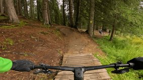 POV: Perspective of a mountain biker navigating down a winding and challenging wooden trail through a bike park. Fun, excitement and thrill of downhill adventures in beautiful mountain environment. - Powered by Shutterstock - Get 15% off with code: PIKWIZARD15