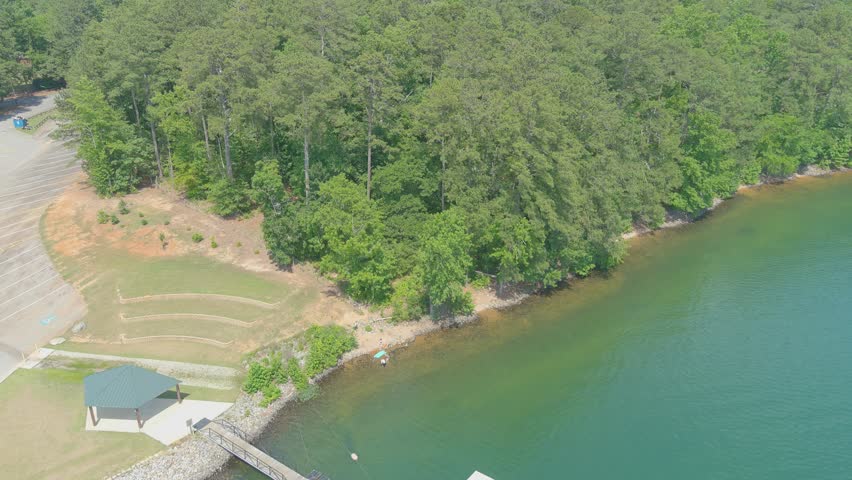 stunning aerial footage of the vast silky green waters of Lake Allatoona surrounded by lush green trees with boat docks along the banks of the lake at Victoria Beach in Acworth Georgia USA