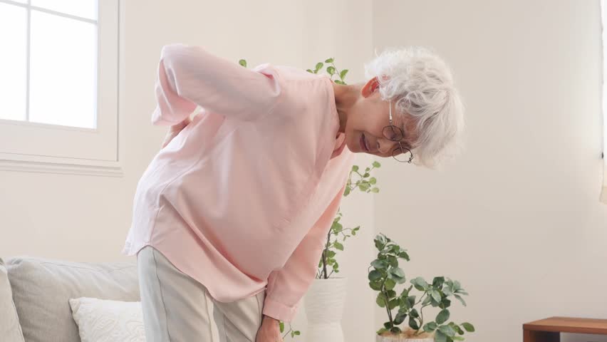 Asian senior woman having a backache in the living room