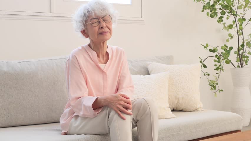 Asian senior woman having the joint pain in the living room
