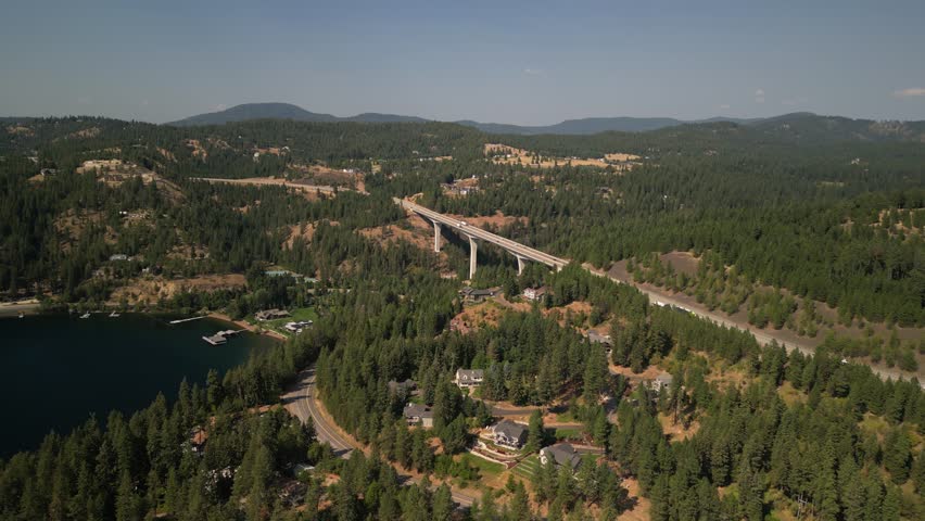 Aerial above homes in mountains along Lake Coeur Dalene Idaho next to Highway 90