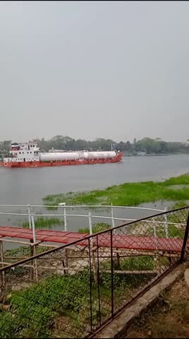Different Objects along with natural nice scenes are seen on the both side of River and a modern Cargo ship is going through the river. Video clip taken in Bangladesh 
