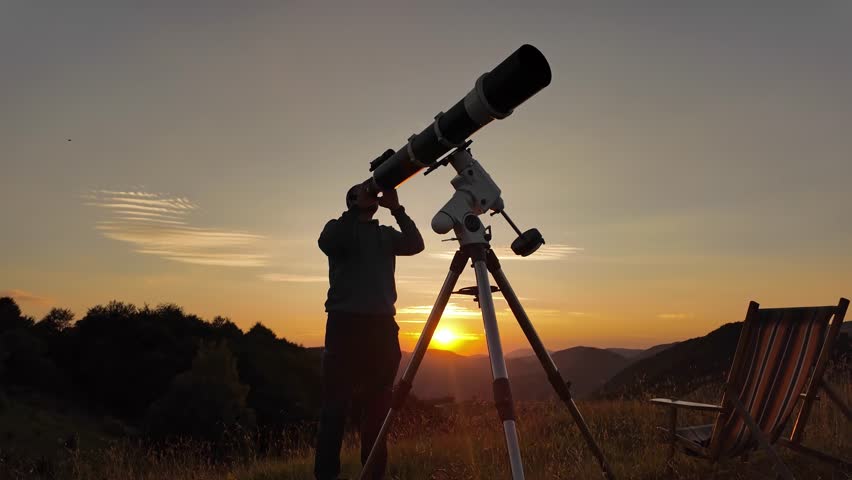 Amateur astronomer looking at the evening skies, observing planets, stars, Moon and other celestial objects with a telescope just before sun down.	
