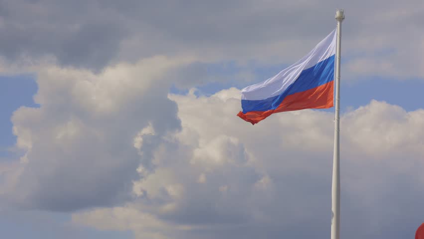 Flag of Russian Federation is flying in air on blue sky and white cumulus clouds. National flag of Russian. shot handheld. High quality 4k footage