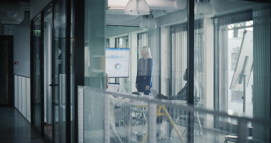Female Manager Making a Presentation to a Board of Directors in a Meeting Room in the Office. Young Executive Using a Digital Interactive Whiteboard to Show Company Performance, Sales and Revenue Data