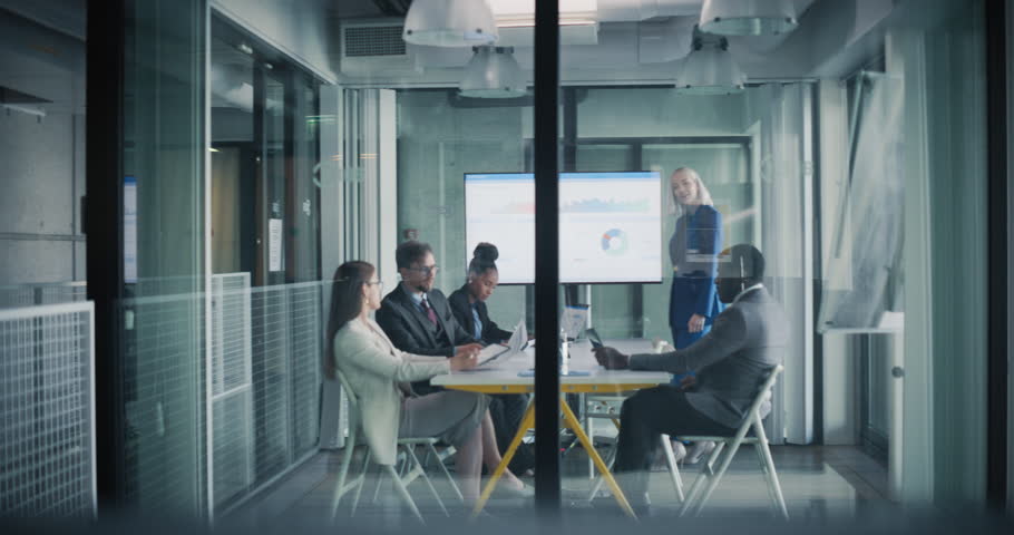 Female Manager Making a Presentation to a Board of Directors in a Meeting Room in the Office. Young Executive Using a Digital Interactive Whiteboard to Show Company Performance, Sales and Revenue Data