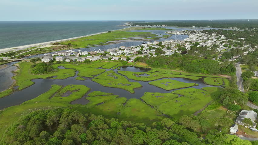 Expansive view of lush green marshland, Atlantic ocean in Cape Cod, idyllic charming homes, aerial panoramic