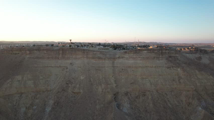  A captivating view of Mitzpe Ramon city from the edge of the crater, showcasing the dramatic cliffside and the expansive desert below.