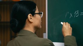 Asian middle-aged teacher writing math equation on chalkboard in classroom - Powered by Shutterstock - Get 15% off with code: PIKWIZARD15