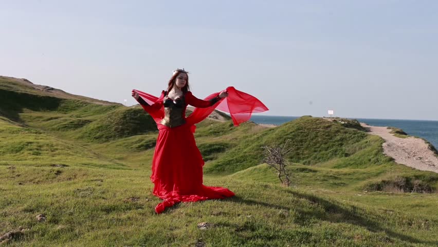  Beautiful red haired girl in metal medieval armor dress with sword standing in warlike pose