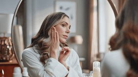 Involved woman lymphatic drainage procedures at mirror place. Closeup smiling lady touching face making facial self massage at home. Calm model doing domestic skin care treatment at light bathroom  - Powered by Shutterstock - Get 15% off with code: PIKWIZARD15