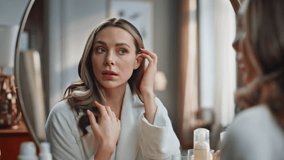 Beautiful lady touching skin looking mirror indoors closeup. Young woman doing face lifting self massage at bathroom. Focused model making mimic gymnastics exercises. Beauty care at house concept - Powered by Shutterstock - Get 15% off with code: PIKWIZARD15