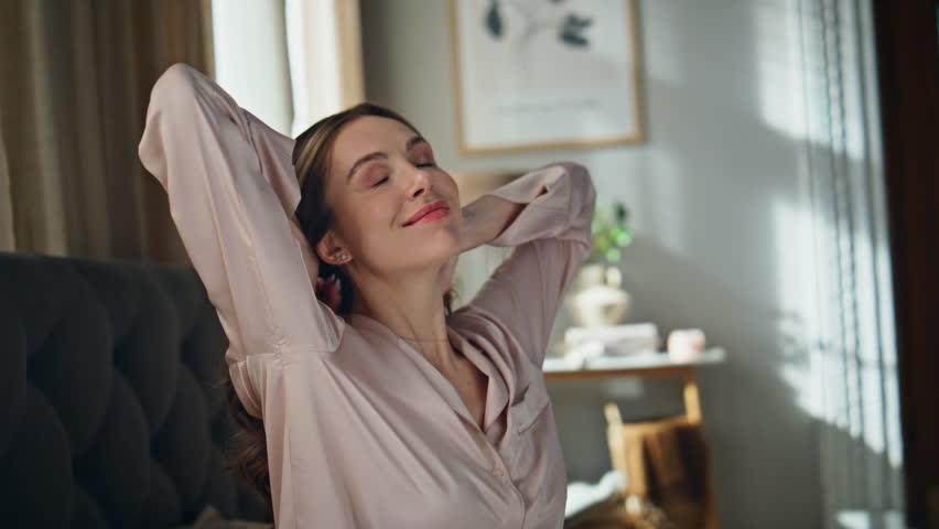 Closeup carefree girl stretching in morning sunlight. Attractive woman waking up full of energy enjoying weekend at home. Happy joyful female greeting new day. Daily routine positive mood concept 
