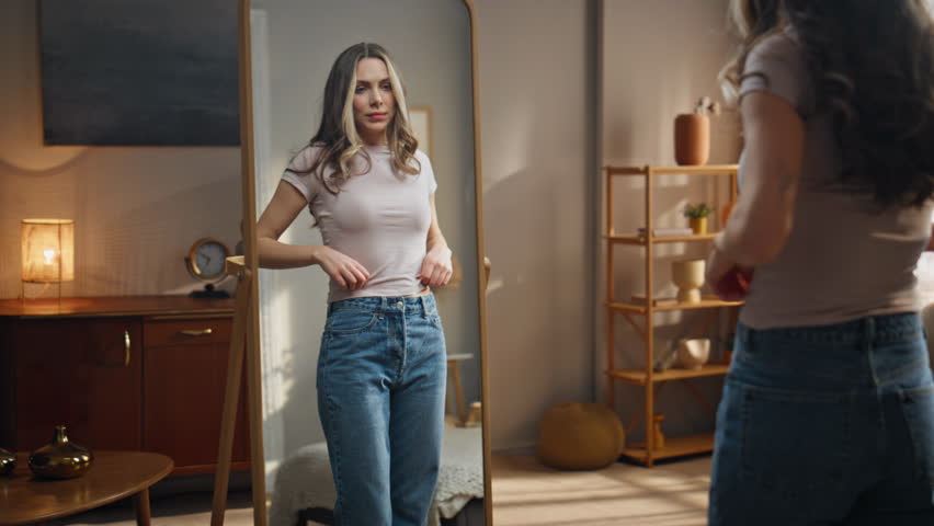 Woman reflection admiring perfect body shape at warm light bedroom. Happy slim model check weight loss results. Attractive girl analyzing fitness achievement at home. Determination success concept 