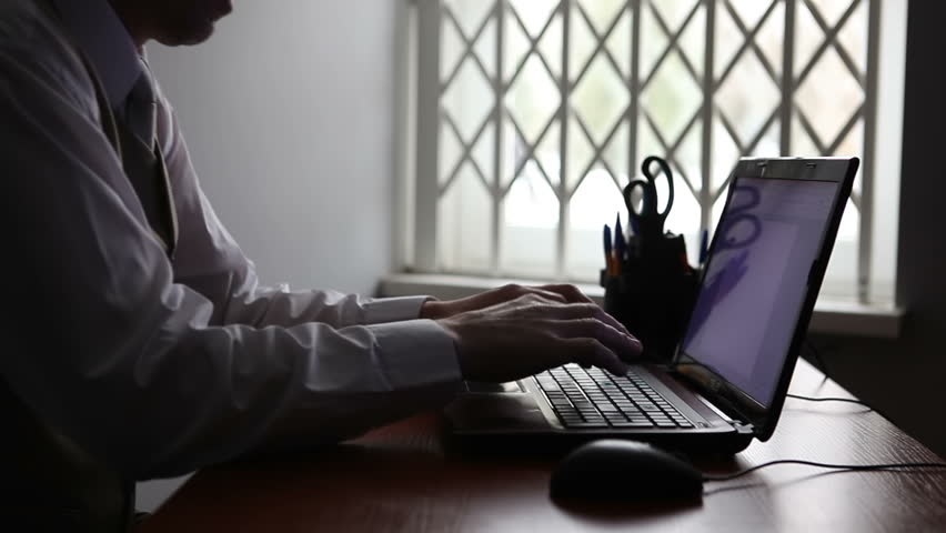 An investigator sits in his office at a computer at a police station.