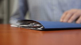 Businessman sitting at desk in office looking through folder with documents. Macro. - Powered by Shutterstock - Get 15% off with code: PIKWIZARD15