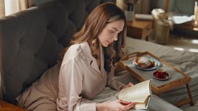 Relaxed woman reading book in bed closeup. Happy attractive girl resting enjoying breakfast coffee at home. Carefree smiling female flipping novel studying in bedroom alone. Morning lifestyle concept  - Powered by Shutterstock - Get 15% off with code: PIKWIZARD15