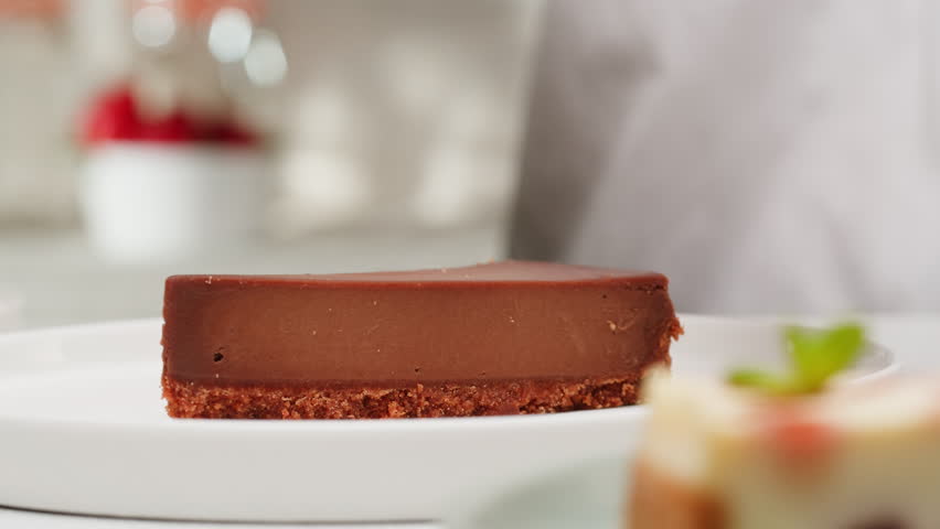 Pastry chef adding liquid chocolate topping on chocolate dessert cheesecake close-up. Cheesecake is a dessert made with a soft fresh cheese , typically cottage cheese, cream cheese, quark or ricotta