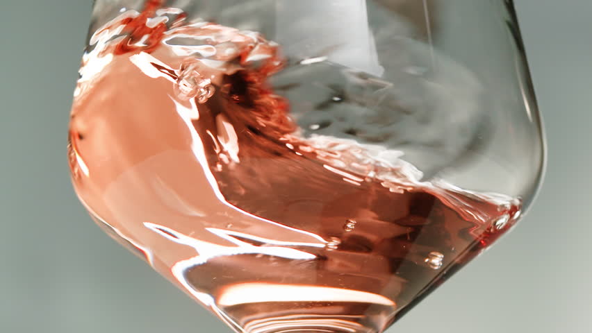 Rose Orange or white wine bottle and glass against a sunset in a peaceful vineyard, pouring of ecological natural wine. Cheers, hands with wine glasses, drinking alcohol.