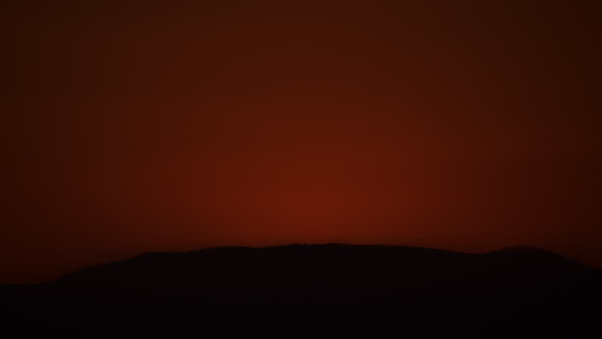 Extreme Closeup of Sun Rising Over a Hill into a Red Sky 4K Zoom Out Timelapse.