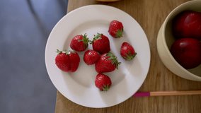 Child’s hand reaching for fresh strawberries on a white plate, surrounded by fruits and a pencil, capturing a simple and healthy snack time moment with vibrant colors and natural light - Powered by Shutterstock - Get 15% off with code: PIKWIZARD15