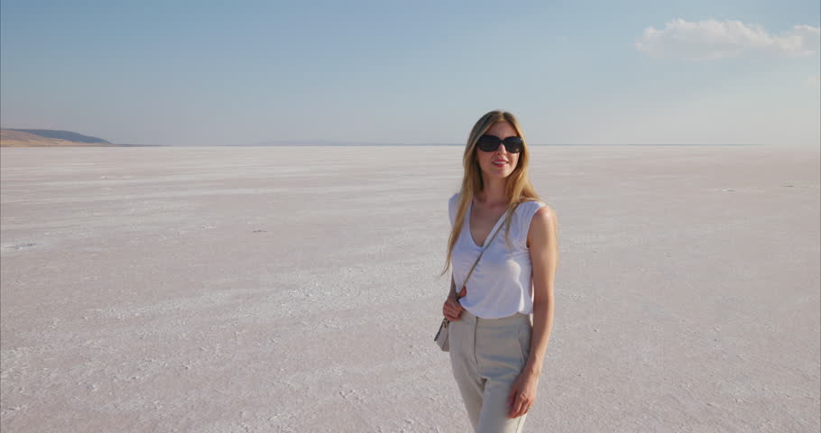 Stunning still images from a video album 'Cappadocia' capturing a scenic moment at Salt Lake Tuz in Turkyie. A woman enjoys the serene and expansive salt flats under a clear blue sky.