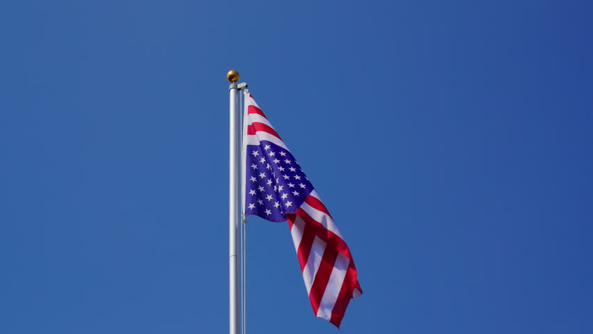 Waving American flag flying upside down on a flagpole, slow motion, medium shot, low angle
