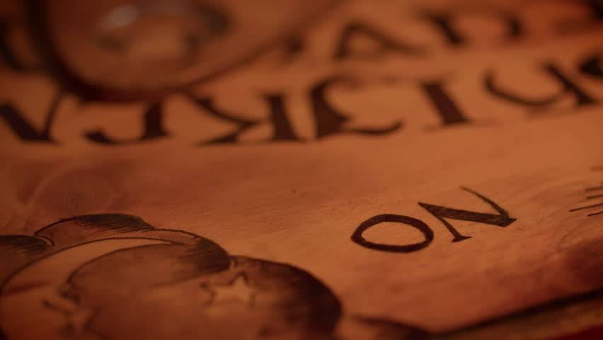 A ouija board pointer is moved to the word "NO" by an invisible force