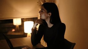 Happy young brunette woman working from home, sitting at desk with laptop, smiling and gazing out of the window. Warm lighting enhances her carefree mood as she contemplates her day - Powered by Shutterstock - Get 15% off with code: PIKWIZARD15