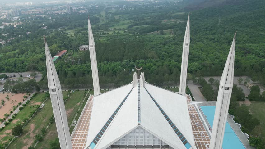 The Shah Faisal Mosque in Islamabad, Pakistan, is an architectural marvel with its modern, minimalist design. Surrounded by lush gardens and set against the backdrop of the Margalla Hills.