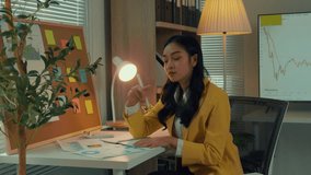 Businesswoman studies financial graphs and charts at her desk, demonstrating focus and expertise in finance. Thoughtful consideration of data evident in her analysis process - Powered by Shutterstock - Get 15% off with code: PIKWIZARD15