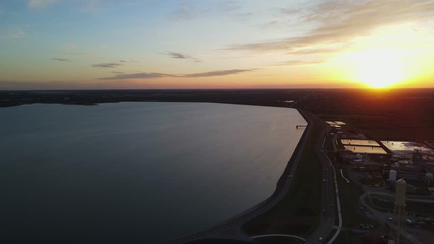 Panoramic aerial overview of vast Lake Hefner alongside highways of Oklahoma City, USA during colorful sunset.